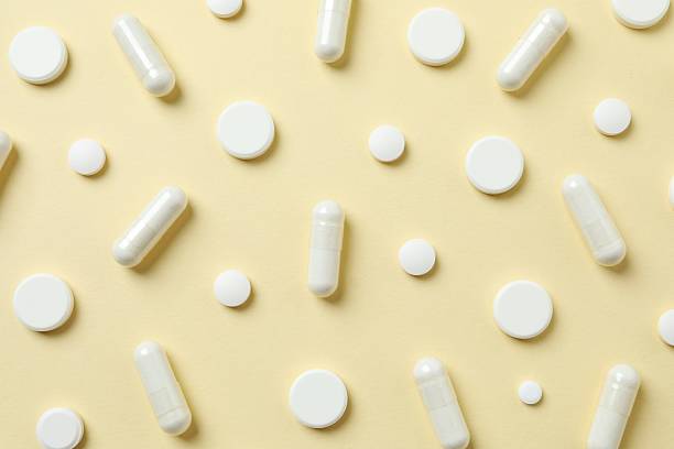 istock Various white pills macro on a color background, top view 2246299843