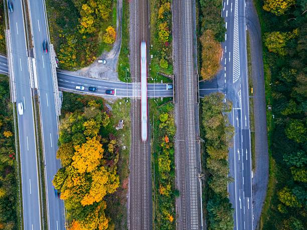 Aerial view of a busy highway and railway intersection surrounded by vibrant autumn foliage.