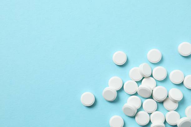 istock White medicine pills on blue background. Pharmacy background 2246300037