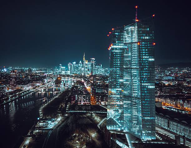 Night view of Frankfurt skyline with illuminated skyscrapers and the Main River, showcasing urban architecture and vibrant city lights.