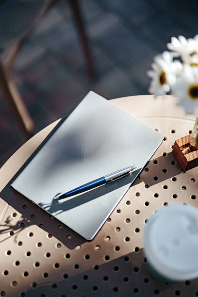 istock Notepad and pen on a table in an outdoor cafe with sunny ambiance 2246303770