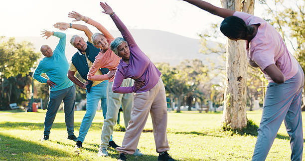 istock Class, stretching and instructor with old people in park for wellness, workout or mobility exercise. Joint friendly training, retirement and learning with senior men and women outdoor for warm up 2246307606