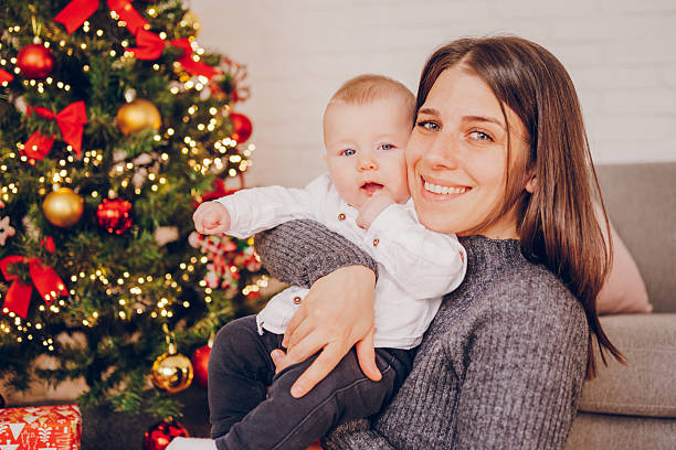 Cheerful mother hugs her baby for Christmas celebrations