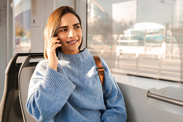 istock Young woman smiling while talking on mobile phone on public transport 2246312699