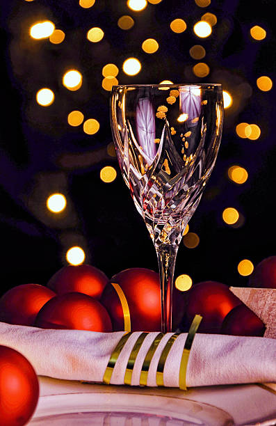 Luxurious Christmas scene featuring a crystal glass, red ornaments and golden bokeh lights, evoking sophistication, warmth, and holiday celebration. Copy space for text, high angle view - Christmas, New Year