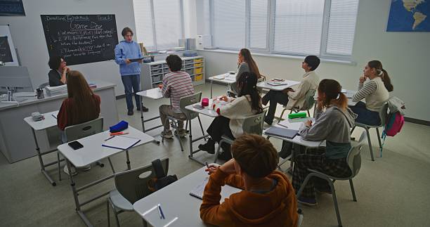 istock Boy in Blue Hoodie Presents Report on Educational Project For Game Development to Classmates 2246314822