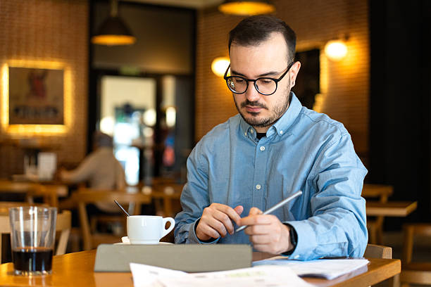 istock Man reviewing financial documents in coffee shop 2246317402