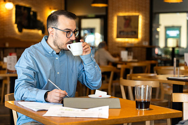 istock Young man reviewing finance documents and drinking coffee 2246317409