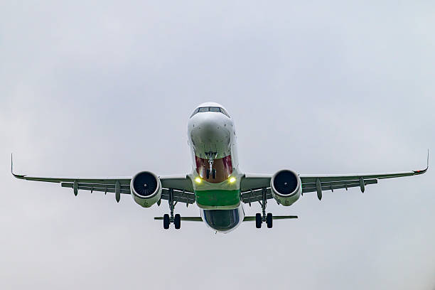 Airplane landing at the airport runway of Schiphol Amsterdam Airport with runway lights in the foreground.