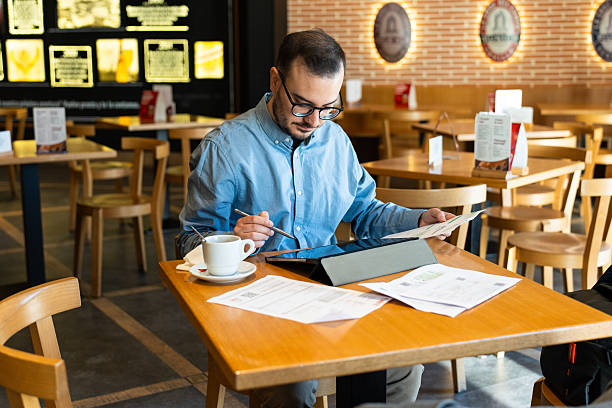 istock Man working remotely, reviewing financial documents in cafe 2246317445