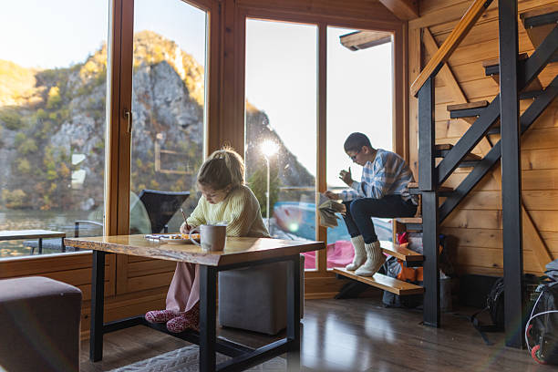 istock Cozy Cabin Interior With Children Studying By Large Windows Overlooking A Lake Scene 2246320836