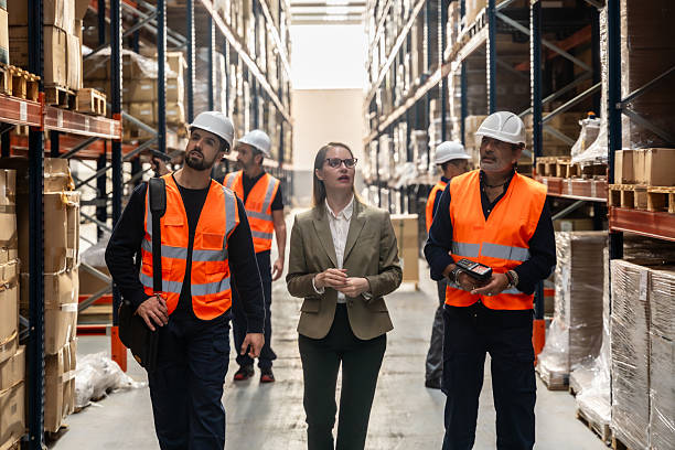 istock Logistics manager supervising warehouse workers walking through aisles 2246324127