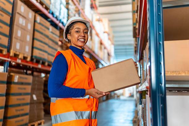 istock Female warehouse worker smiling holding package in logistics facility 2246324152