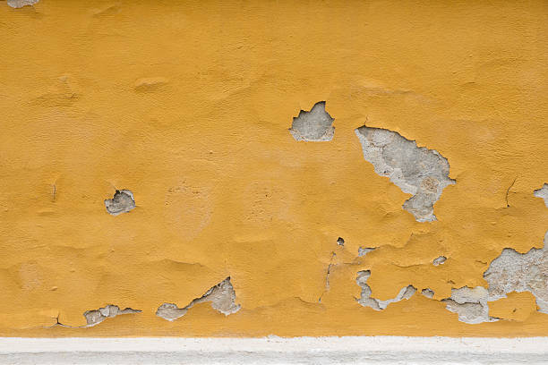 Severely Weathered and Textured Old Orange Wall with Peeling Paint and Exposed Plaster