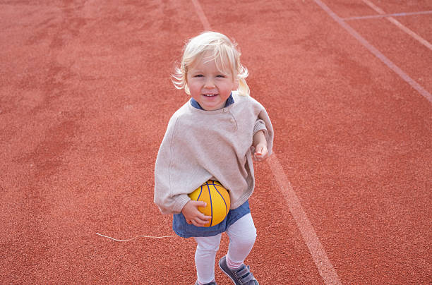 Female young basketball player standing on basketball court. Confident girl is holding ball