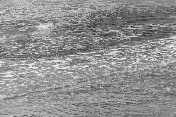 Calm sea waves with gentle foam captured in black and white on the Cyprus coast, creating a serene and minimalist seascape