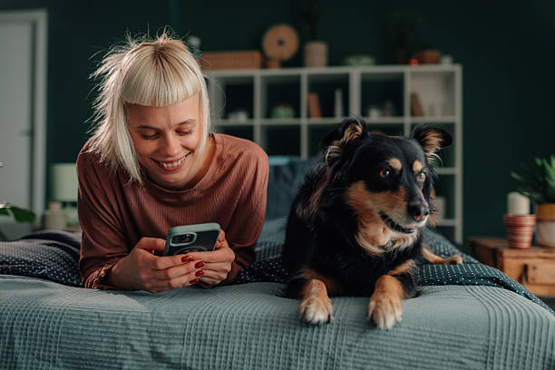 istock Woman smiling using phone next to dog in bed 2246327796