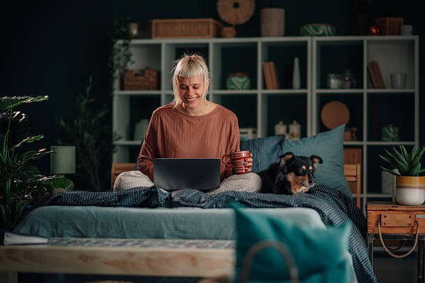 istock Woman working from home with dog on cozy bed 2246327892