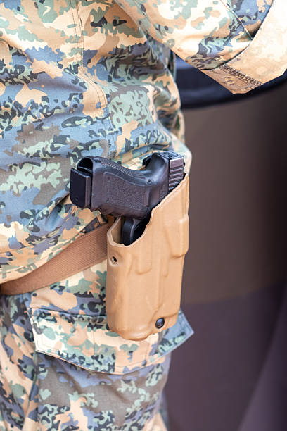 A soldier in camouflage carries a weapon in a sturdy plastic holster