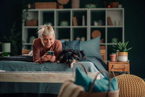 istock Woman relaxing in bed using phone with dog 2246328142