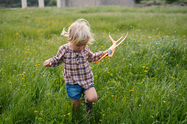 A blonde girl walking on the grass in summer, observing flowers and blades of grass. High quality photo