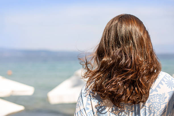 Woman relaxing by the sea, looking at the clear blue ocean