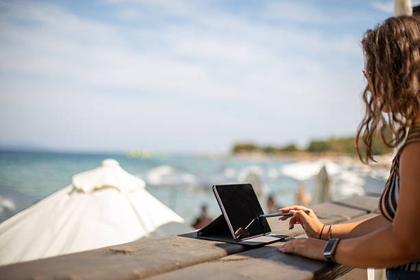 istock Woman working on tablet with stylus at beach 2246338912