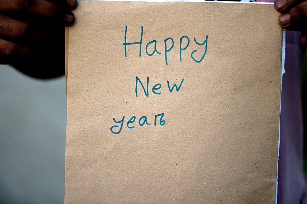 istock Handwritten happy new year message on a brown paper card held by hands 2246339322