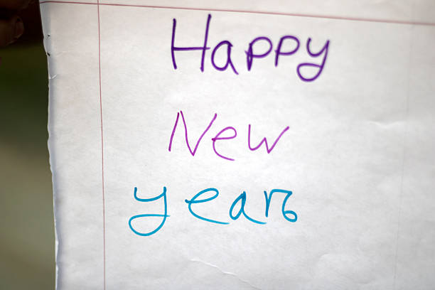 A simple and cheerful handwritten message that says Happy New Year in purple and blue ink on a plain white paper, conveying festive wishes for the upcoming year.