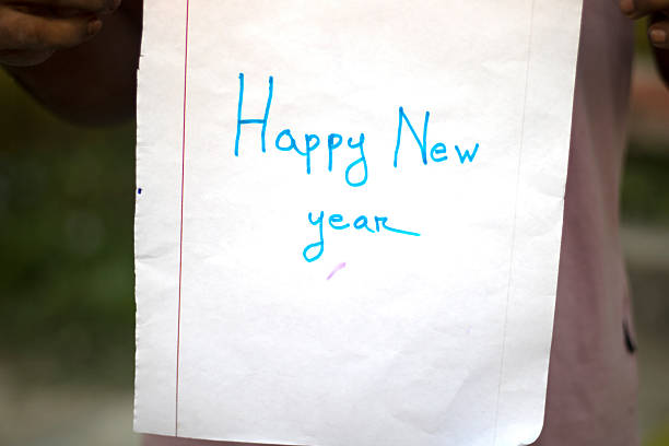 A close-up shot of a white paper with 'Happy New Year' written in blue ink. The message is handwritten, conveying a festive and personal greeting for the upcoming year.