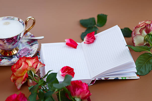 Romantic morning with roses, a notebook and a cup of cappuccino.