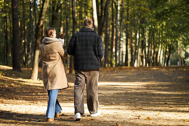 istock Couple Walking Together in Autumn Forest Pathway 2246339911