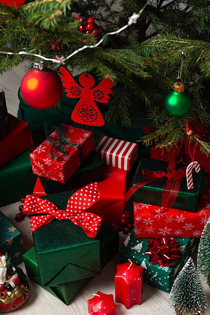 istock A festive display of green and red gift boxes under a beautifully decorated Christmas tree, complemented by candles and traditional ornaments, evoking warmth and holiday cheer 2246340113