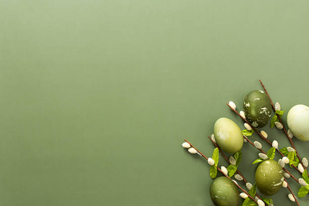 istock Colorful Easter eggs in shades of green are displayed alongside delicate branches adorned with flowers, set against a soft green backdrop, evoking a spring celebration 2246341592