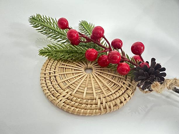 Festive Arrangement with Pine Branch, Red Berries, Pine Cone, and Woven Coaster on a Light Background for Holiday Themes