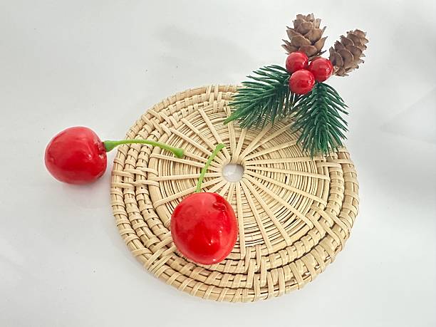 istock Bountiful Christmas Decor Featuring Red Cherries, Green Pine Leaves, and Pine Cones on a Round Woven Straw Mat for Festive Home Styling 2246342637