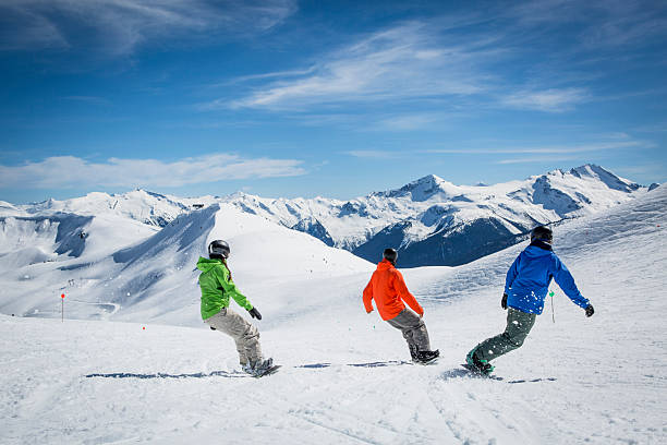Snowboarding instructor teaches group of students at Whistler ski resort on a sunny day in winter, Whistler, British Columbia