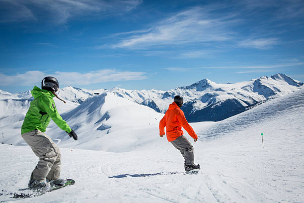 Snowboarder instructor teaches young woman how to snowboard on a sunny winter day, Whistler, B.C.