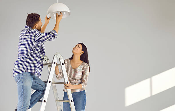 istock Happy loving couple changing light bulb in new apartment 2246343383