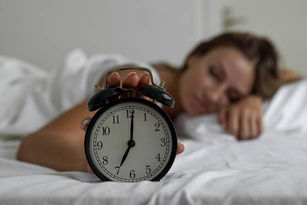 istock Alarm clock ringing with woman sleeping in bed in the background 2246344084