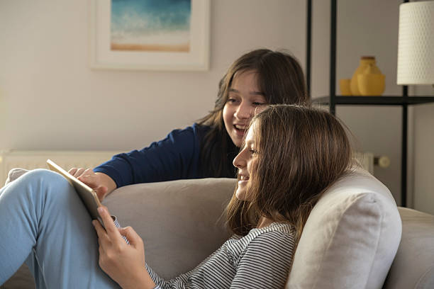 istock Sisters sharing digital tablet at home, laughing and enjoying online content 2246345170