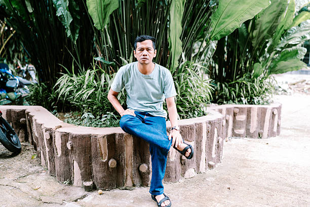 istock Asian Man Posing on Decorative Wall in Green Garden 2246346016