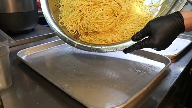 istock Draining a large volume of cooked spaghetti onto metal trays 2246350517