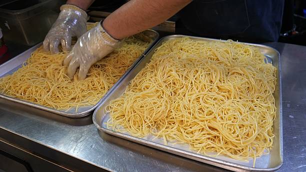 istock Draining a large volume of cooked spaghetti onto metal trays 2246350537