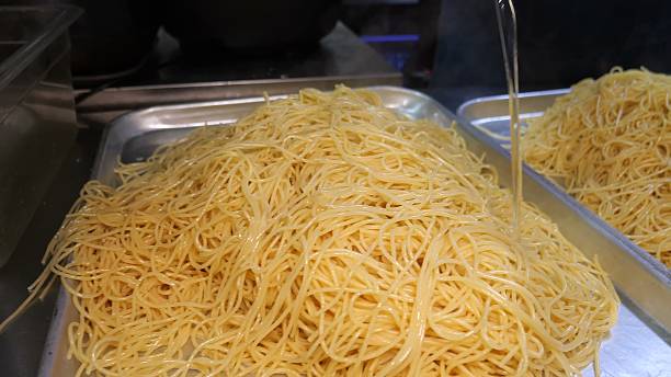 istock Draining a large volume of cooked spaghetti onto metal trays 2246350576