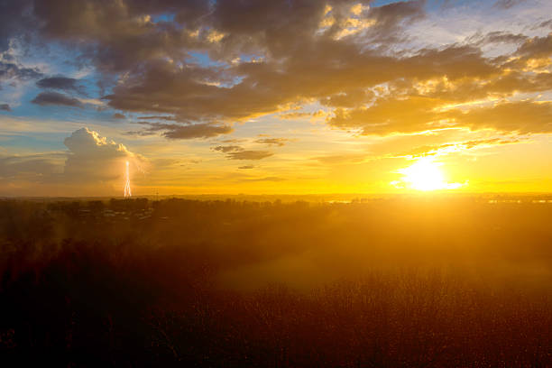 Bright lightning bolts light up distance as sun sets, creating stunning display of natures power beauty