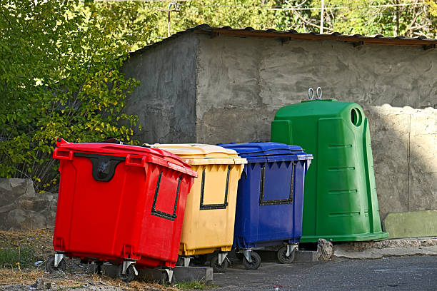 istock Three trash cans are lined up next to a building 2246357907