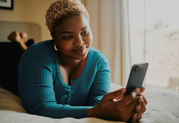 istock Young Black Woman Lying on Bed Using Smartphone 2246360828