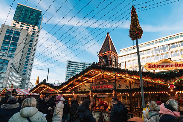 Berlin, Germany – November 30, 2024: Visitors stand in front of the “Holzkohlengrill” stall at the Breitscheidplatz Christmas market in Berlin, illuminated with holiday lights.