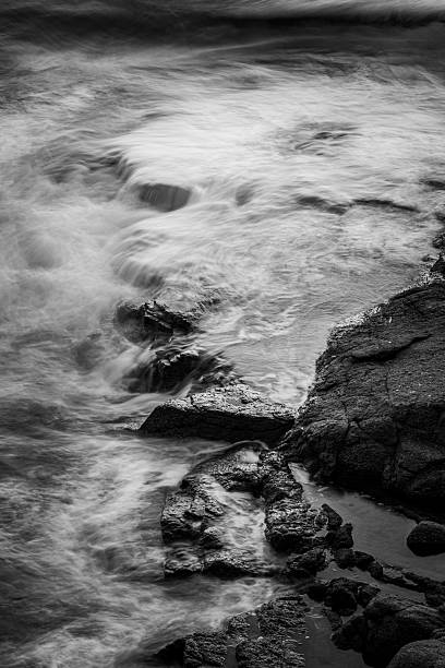istock Monochrome Waves Crashing on Rocky Shore 2246363416